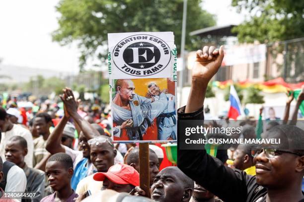 Supporter of Malian Interim President holds up a sign with the images of President of Russia Vladimir Putin kicking President of France Emmanuel...