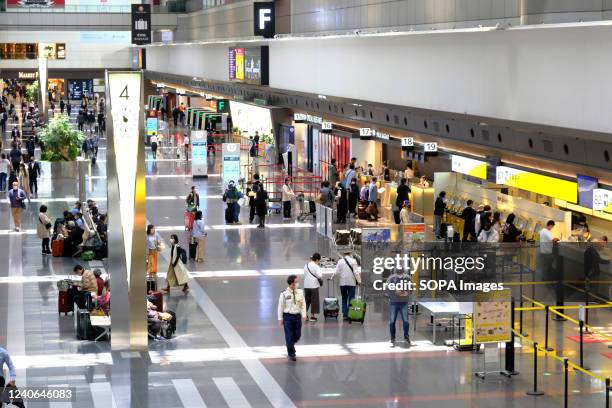 Passengers wearing face masks as a preventive measure against the spread of covid-19 are seen at the Tokyo International Airport, commonly known as...