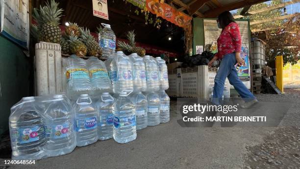 Woman walks past water bottles displayed for sale in the Paine commune, Santiago, on May 6, 2022. - A new referendum will take place in Chile on...