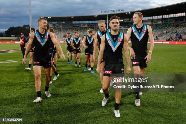 Ollie Wines, Karl Amon and Sam Hayes of the Power leave the field after a win during the 2022 AFL Round 09 match between the North Melbourne...