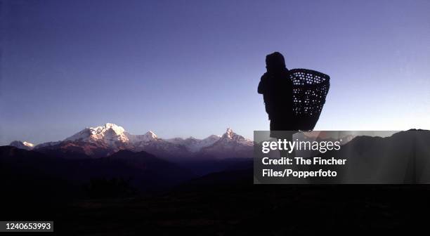 Nepalese Sherpa looking across the Himalayas to Annapurna and Dhaulagiri before setting off on a trek to the capital, circa 1969.