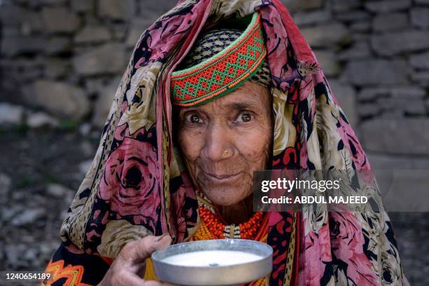 Kalash tribe woman wearing a traditional dress drinks milk as a part of ritual on the first day of 'Joshi' festival to welcome the arrival of spring...