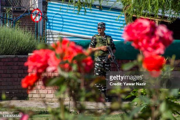 An Indian paramilitary trooper stands guard in front the roses in full bloom, on May 14, 2022 in Srinagar, the summer capital of Indian Administered...