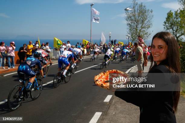 Spectator holds a Neapolitan pizza as riders compete during the 8th stage of the Giro d'Italia 2022, 153 kilometers between Napoli and Napoli,...