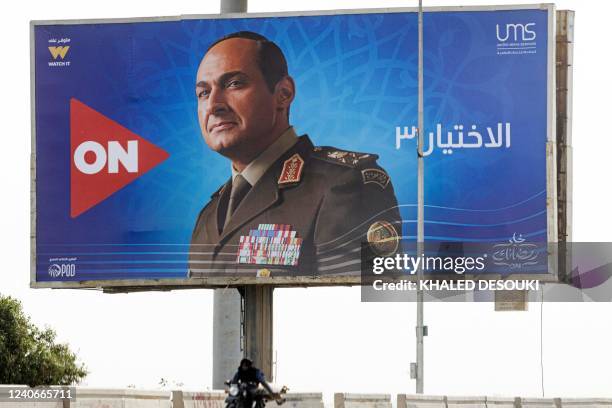 Vehicles drive along a highway beneath a billboard showing an advertisement for the Ramadan television series "Al-Ikhtiyar 3" with Egyptian actor...