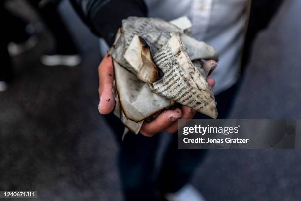 People collect the remains of a burned Koran that was set on fire during an election meeting for the Stram Kurs party in Hallunda on May 14, 2022 in...