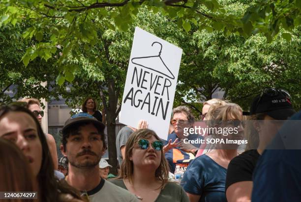 Protester displays a symbolic coat hanger placard that says "Never again" at a pro abortion rights rally. People from many different cities gathered...