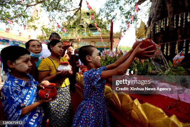 Girl waters a Bodhi Tree at the Shwedagon Pagoda in Yangon, Myanmar, May 14, 2022. Myanmar people, especially Buddhists, ritually watered sacred...