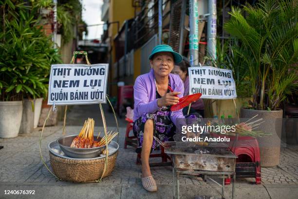Street seller grills pork meat beside a river walkway in Hoi An, Vietnam on May 14, 2022.