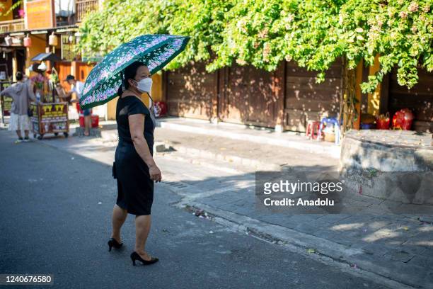 Woman holds an umbrella to stay cool amid searing midday heat in Hoi An, Vietnam on May 14, 2022.