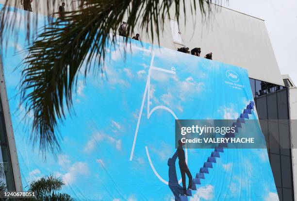 Workers set up the official poster of the 75th Cannes Film Festival on the facade of the Palais des Festivals, in Cannes, southeastern France, on May...