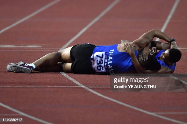 Philippines' Aries Toledo Banes and Thailands Suttisak Singkhon hug on the ground after finishing the men's 1500m decathlon final during the 31st...