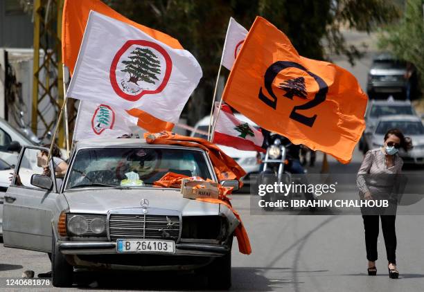 The flags of the "Lebanese Forces" and the "Free Patriotic Movement" Christian political parties, and the Lebanese national flag, fly from a vehicle...