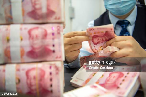 Staff member counts renminbi at a bank in Haian, Nantong city, East China's Jiangsu province, May 15, 2022. According to the People's Bank of China ,...