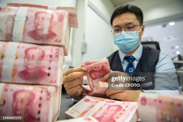 Staff member counts renminbi at a bank in Haian, Nantong city, East China's Jiangsu province, May 15, 2022. According to the People's Bank of China ,...