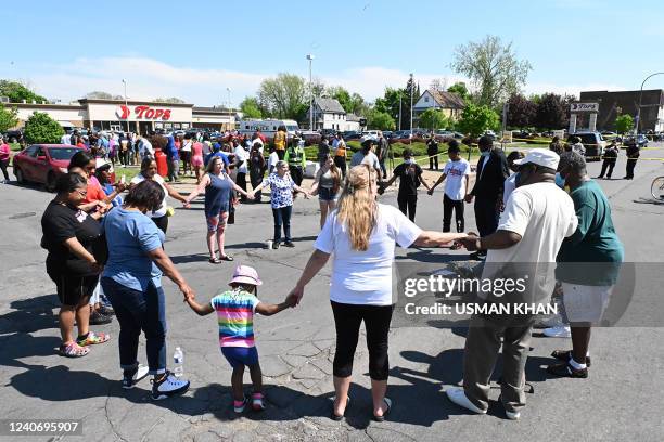 Mourners hold hands near a Tops Grocery store in Buffalo, New York, on May 15, 2022. - Grieving residents from the US city of Buffalo held vigils...