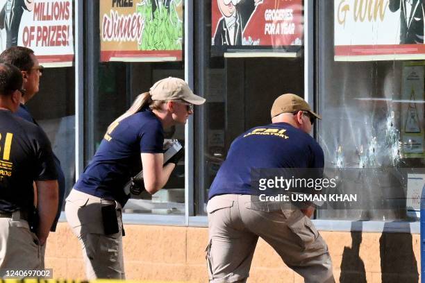 Agents look at bullet impacts in a Tops Grocery store in Buffalo, New York, on May 15 the day after a gunman shot dead 10 people. - Grieving...