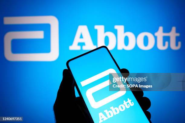 In this photo illustration the Abbott Laboratories logo seen displayed on a smartphone and in the background.