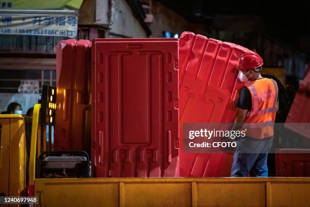 Workers install a fence to seal off a neighborhood at dusk in Guangzhou, Guangdong Province, China, May 15, 2022. COVID-19 Prevention and Control...