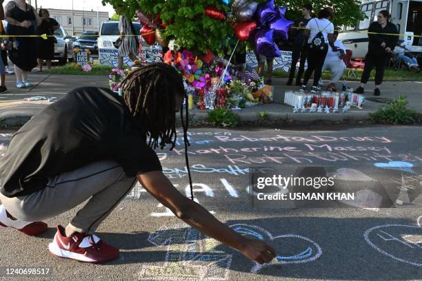 People leave messages at a makeshift memorial near a Tops Grocery store in Buffalo, New York, on May 15 the day after a gunman shot dead 10 people. -...