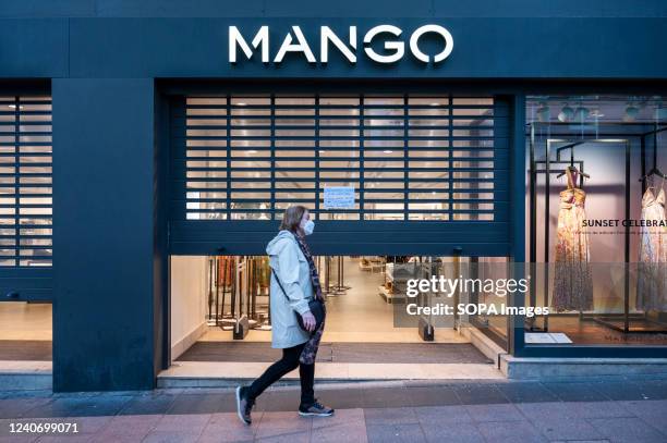 Pedestrian walks past a closing Spanish multinational clothing brand Mango store in Spain.