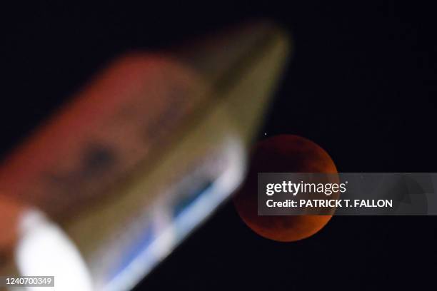 The blood moon is seen during a total lunar eclipse by an illuminated monument of the SpaceX Falcon Heavy rocket in Hawthorne, California on May 15,...