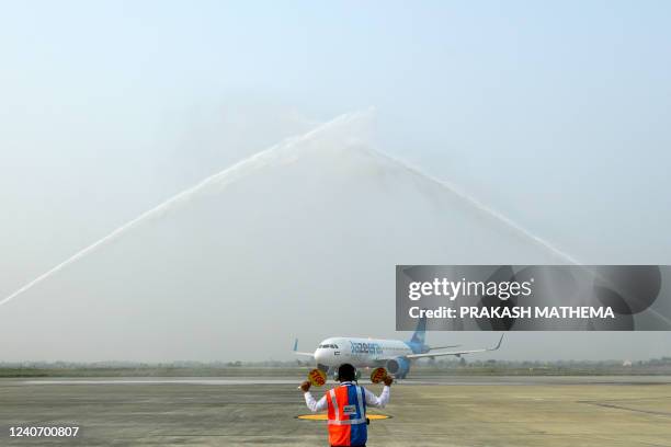 Ground staff directs a Jazeera Airways aircraft to park as it receives a water cannon salute upon landing at the newly built Gautam Buddha...