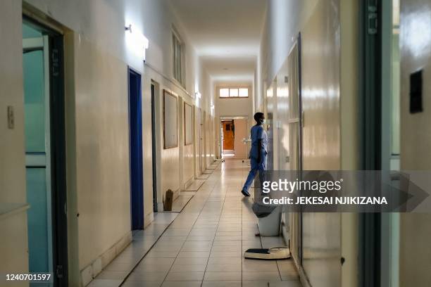 Nurse walks towards an open door along a hospital corridor in a medical ward at a local hospital in Harare on April 26, 2022. - Low salaries and poor...