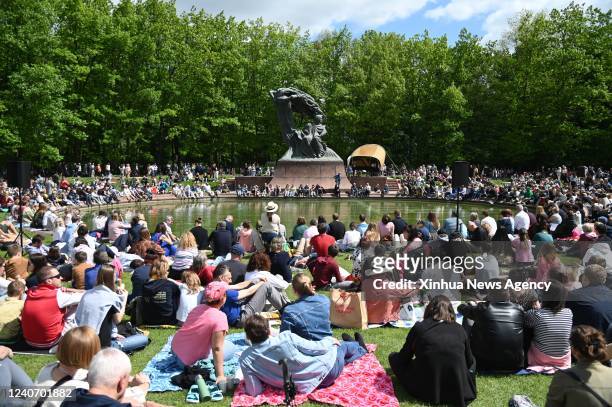 People sit on the grass and enjoy the music of Frederic Chopin performed by a pianist during an open-air Chopin concert at the Royal Lazienki Park in...