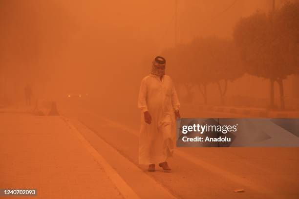 Man protects his face as dust cover the city during sandstorm in Baghdad, Iraq on May 16, 2022. Visibility degraded in traffic due to the sandstorm.