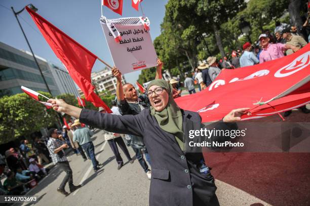 Woman chants slogans as she holds a large flag of Tunisia during a demonstration held by supporters of the movement Citizens Against the Coup - the...