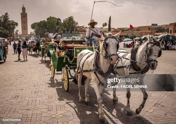 Tourists ride in a horse-drawn carriage in Jemaa el-Fnaa square in Morocco's Marrakesh on May 12, 2022. - Marrakech, the Morocco's tourist showcase...