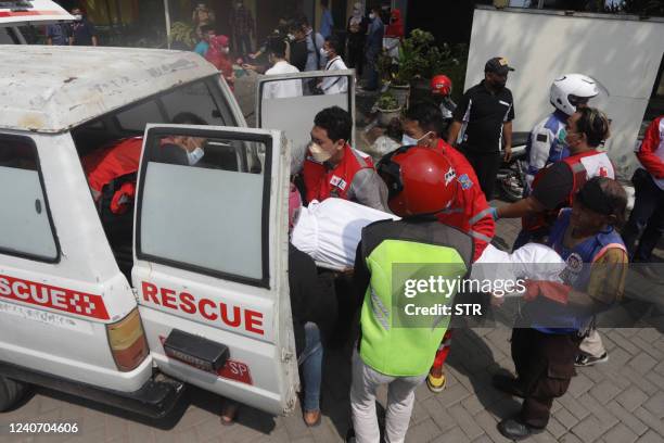 Medical workers load a victim's body into a vehicle after a bus crash, to transport to their family at a hospital in Mojokerto on May 16, 2022. - At...