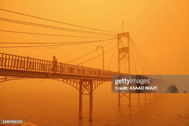 Man walks along a pedestrian bridge along the Euphrates river in the city of Nasiriyah in Iraq's southern Dhi Qar province on May 16, 2022 amidst a...