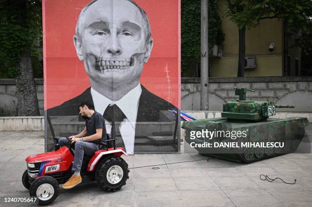 Member of the Roma "ARESEL" NGO pulls with a tractor a Russian tank mockup past a portrait of Russian President Vladimir Putin, during a protest in...