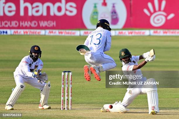 Bangladesh's Mahmudul Hasan Joy plays a shot as Sri Lanka's Kusal Mendis jumps next to wicketkeeper Niroshan Dickwella during the second day of the...