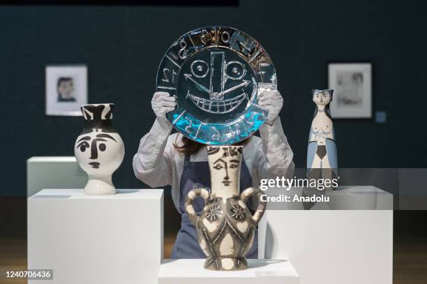 An art handler holds a silver repousse plate titled âVisage en forme d'Horlogeâ by Pablo Picasso , estimate: Â£30,000-50,000 during a photo call for...