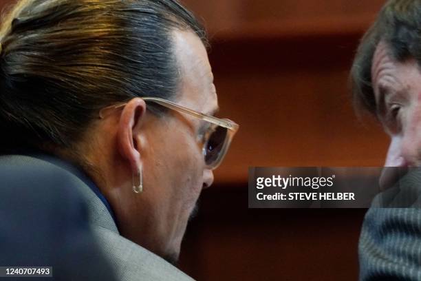 Actor Johnny Depp talks to attorney Ben Chew in the courtroom at the Fairfax County Circuit Courthouse in Fairfax, Virginia, on May 16, 2022. - Actor...