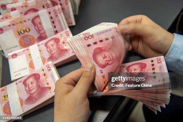 Clerk counts renminbi banknotes at a bank outlet in Hai'an in east China's Jiangsu province Sunday, May 15, 2022. The International Monetary Fund has...