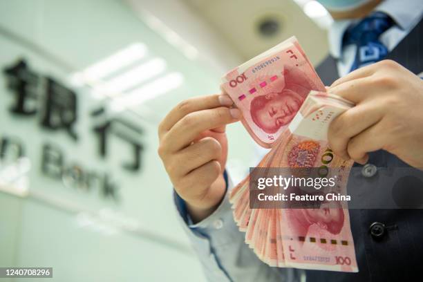 Clerk counts renminbi banknotes at a bank outlet in Hai'an in east China's Jiangsu province Sunday, May 15, 2022. The International Monetary Fund has...