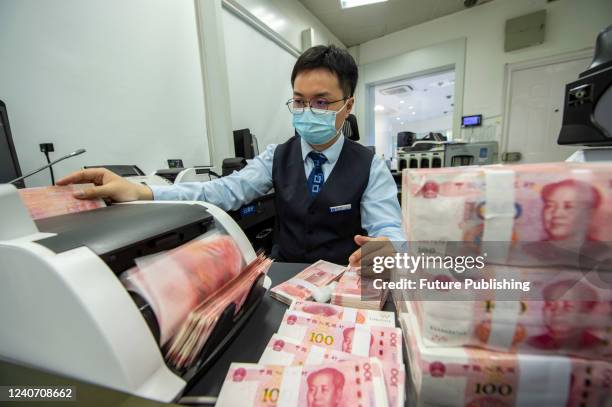 Clerk counts renminbi banknotes at a bank outlet in Hai'an in east China's Jiangsu province Sunday, May 15, 2022. The International Monetary Fund has...