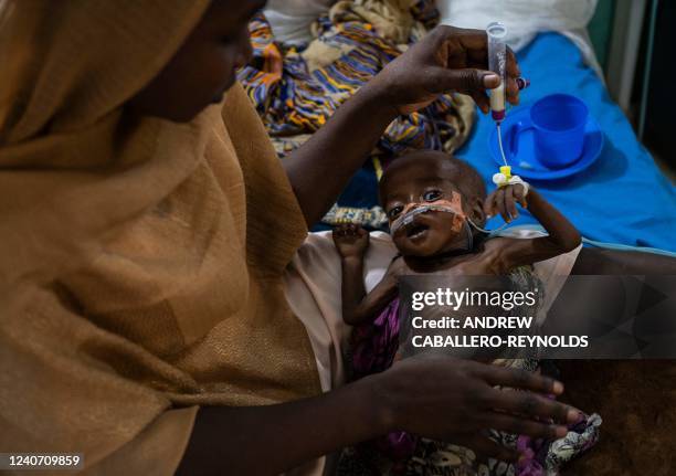 Graphic content / TOPSHOT - Mariam Ali feeds her malnourished son Hassan Ali in the section for critical care patients in the ALIMA managed nutrition...