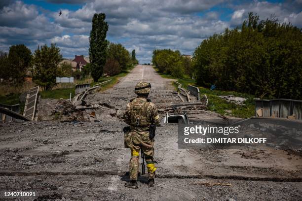 Soldier of the Kraken Ukrainian special forces unit observes the area at a destroyed bridge on the road near the village of Rus'ka Lozova, north of...