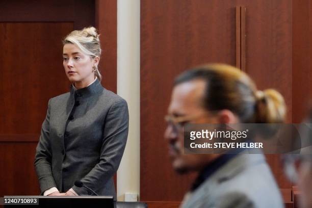 Actors Amber Heard and Johnny Depp watch as the jury leave the courtroom for a lunch break at the Fairfax County Circuit Courthouse in Fairfax,...