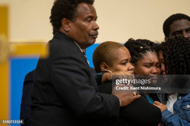 Tiffany Whitfield, left, and Lauren Gibson, right, comforts Laurell Robertson, center, during a news conference with Attorney Ben Crump and other...