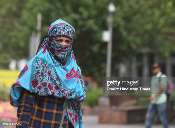 Woman cover herself from the harsh sunlight on hot weather afternoon, at Connaught Place on May 16, 2022 in New Delhi, India. The record-breaking...