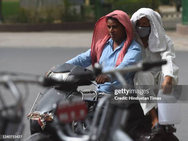 Men cover thier head to protect themselves from the harsh sunlight on hot weather afternoon, at Connaught Place on May 16, 2022 in New Delhi, India....