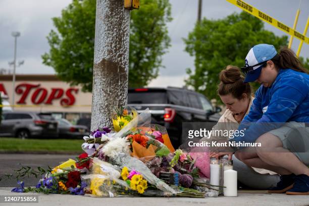 Carlee Taggart of Chicago and Robyn Harpell, of Virginia Beach light candles at a makeshift memorial near the scene of a mass shooting at Tops...