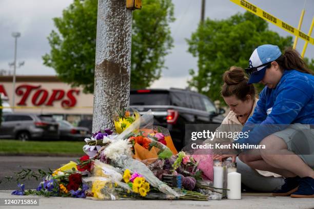 Carlee Taggart of Chicago and Robyn Harpell, of Virginia Beach light candles at a makeshift memorial near the scene of a mass shooting at Tops...