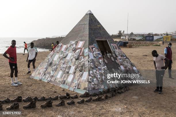 Men look on at an art installation by Senegalese Artist, Yakhya Ba, along Dakars sea promenade on May 11, 2022. - The isntallation is an evocation...